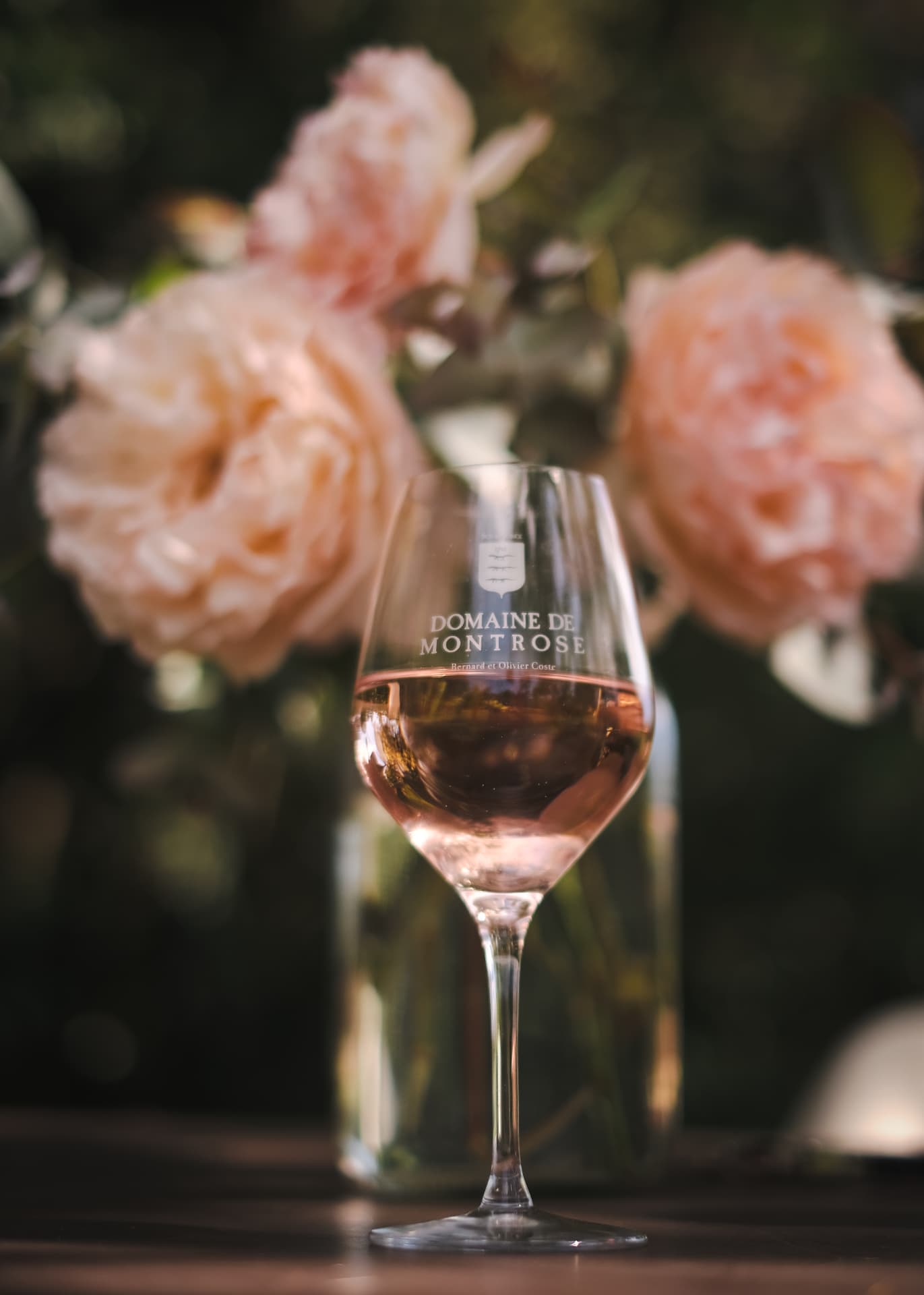 Verre de rosé du Domaine de Montrose devant des roses, sur une table en bois